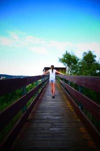 Rear view of man walking on footbridge