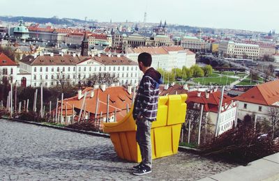 Rear view of man standing against buildings in city