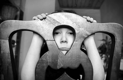 Close-up portrait of boy looking at camera through chair