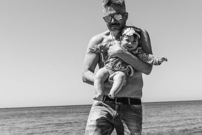 Full length of father with son at beach against sky