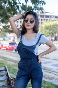 Portrait of young woman wearing sunglasses while sitting on bench