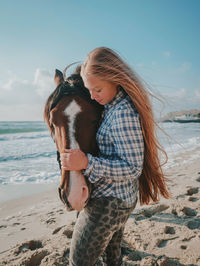 Young woman standing by sea at beach against sky