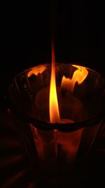 Close-up of illuminated tea light candle in darkroom