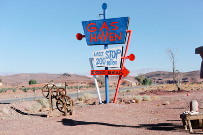 Road sign on field against clear sky