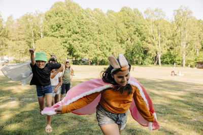 Girl wearing rabbit headband running with friends while playing at summer camp