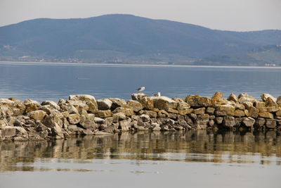Scenic view of lake by mountains against sky