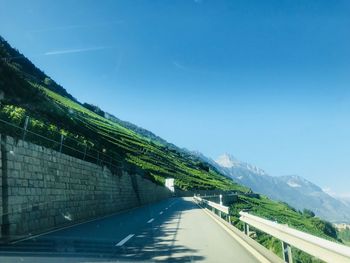 Road by mountain against blue sky