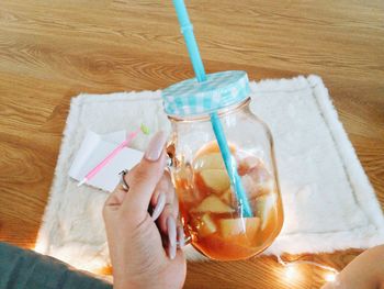 Close-up of cropped hand holding drink jar at home