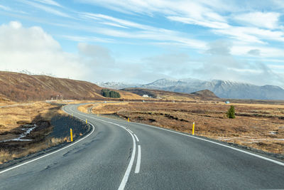 Road leading towards mountains against sky in iceland