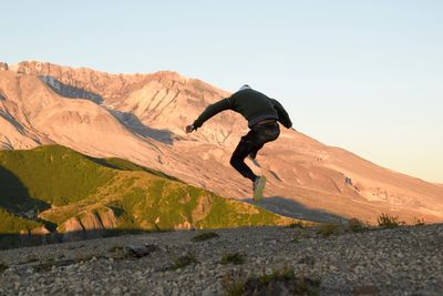 Man jumping on mountain against clear sky