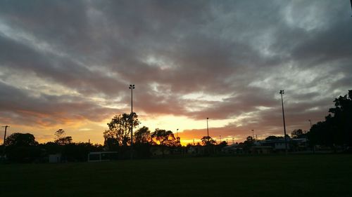 Scenic view of landscape against cloudy sky at sunset