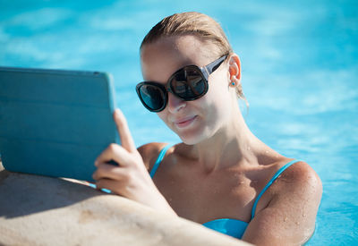 Woman holding digital tablet in swimming pool