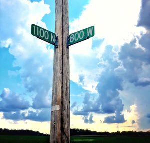 Low angle view of road sign on field against sky