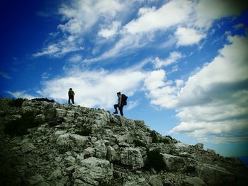 People on rock against sky