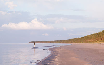 Woman walking along the water on a deserted beach