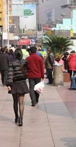 Rear view of people walking on sidewalk