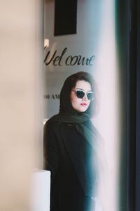 Portrait of woman standing by text on wall