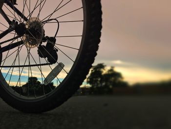 Close-up of bicycle wheel against sky during sunset