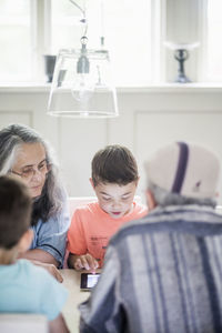 Grandparents looking at boy using digital tablet at home