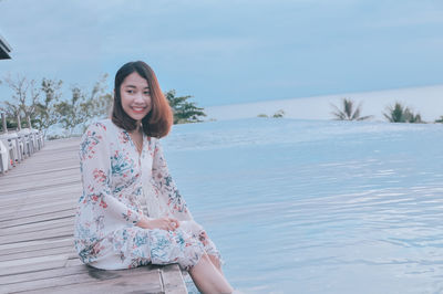 Portrait of smiling woman sitting against sky