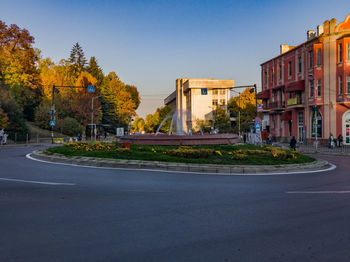 Empty road by buildings against clear sky
