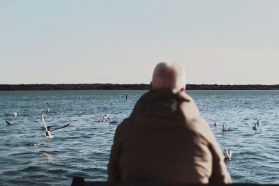 Rear view of man on sea against clear sky