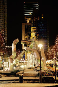 Statue against illuminated city at night