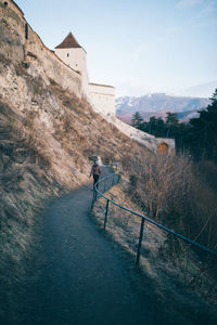 Rear view of woman walking on mountain against sky