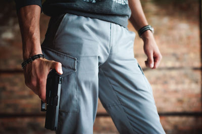 Midsection of man holding gun