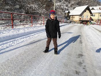Full length of boy standing on road during winter