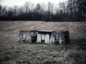 Old barn on field against trees