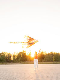 Rear view of man standing against orange sky