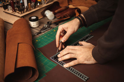 Leatherworker draws, measures with ruler. tanner works with leather, small business, production.