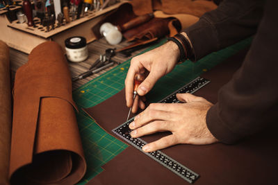 Leatherworker draws, measures with ruler. tanner works with leather, small business, production.