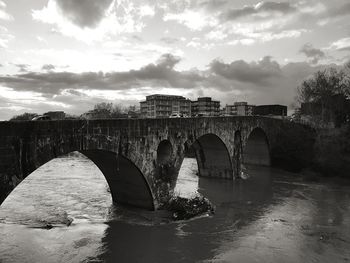 Arch bridge over river against sky during sunset