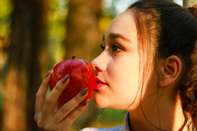 Close-up of young woman smelling apple