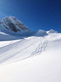 Scenic view of snowcapped mountains against clear blue sky