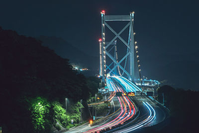 Illuminated light trails on road against sky at night