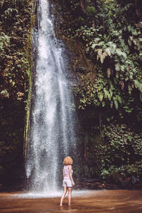 Full length of woman standing by waterfall