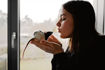 Side view of woman looking through window