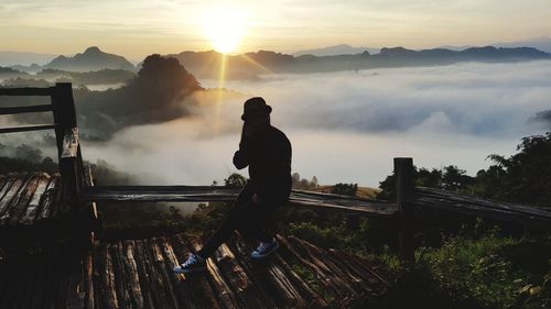 Silhouette man standing on mountain against sky during sunset