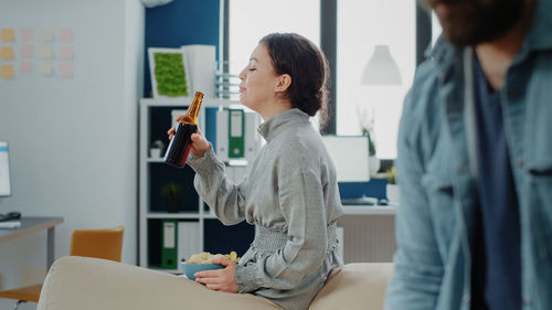 Side view of female friends using mobile phone while sitting at home