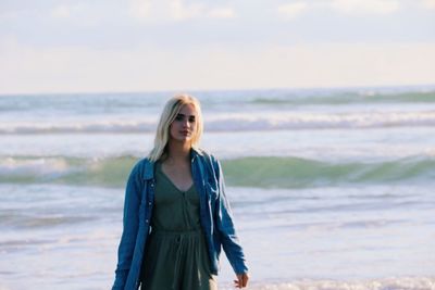 Smiling young woman walking by sea at beach