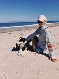 Full length of smiling woman with dog at beach