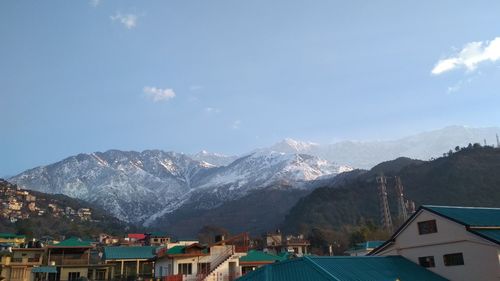 Houses by snowcapped mountains against sky