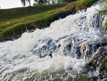 Scenic view of waterfall in forest against sky