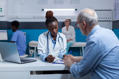 Female doctor helping patient in paperwork at medical clinic