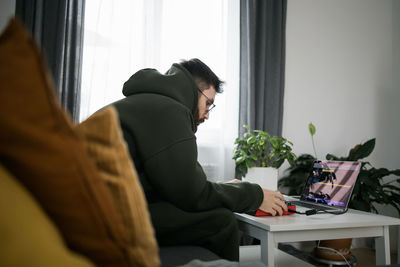 Side view of woman using laptop at home