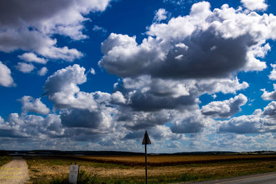 Road amidst field against sky