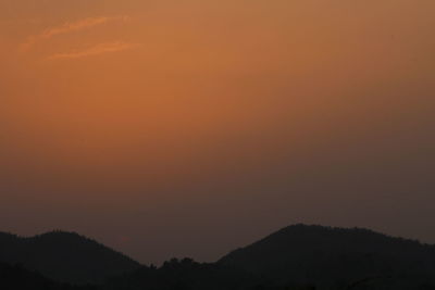 Scenic view of silhouette mountains against orange sky